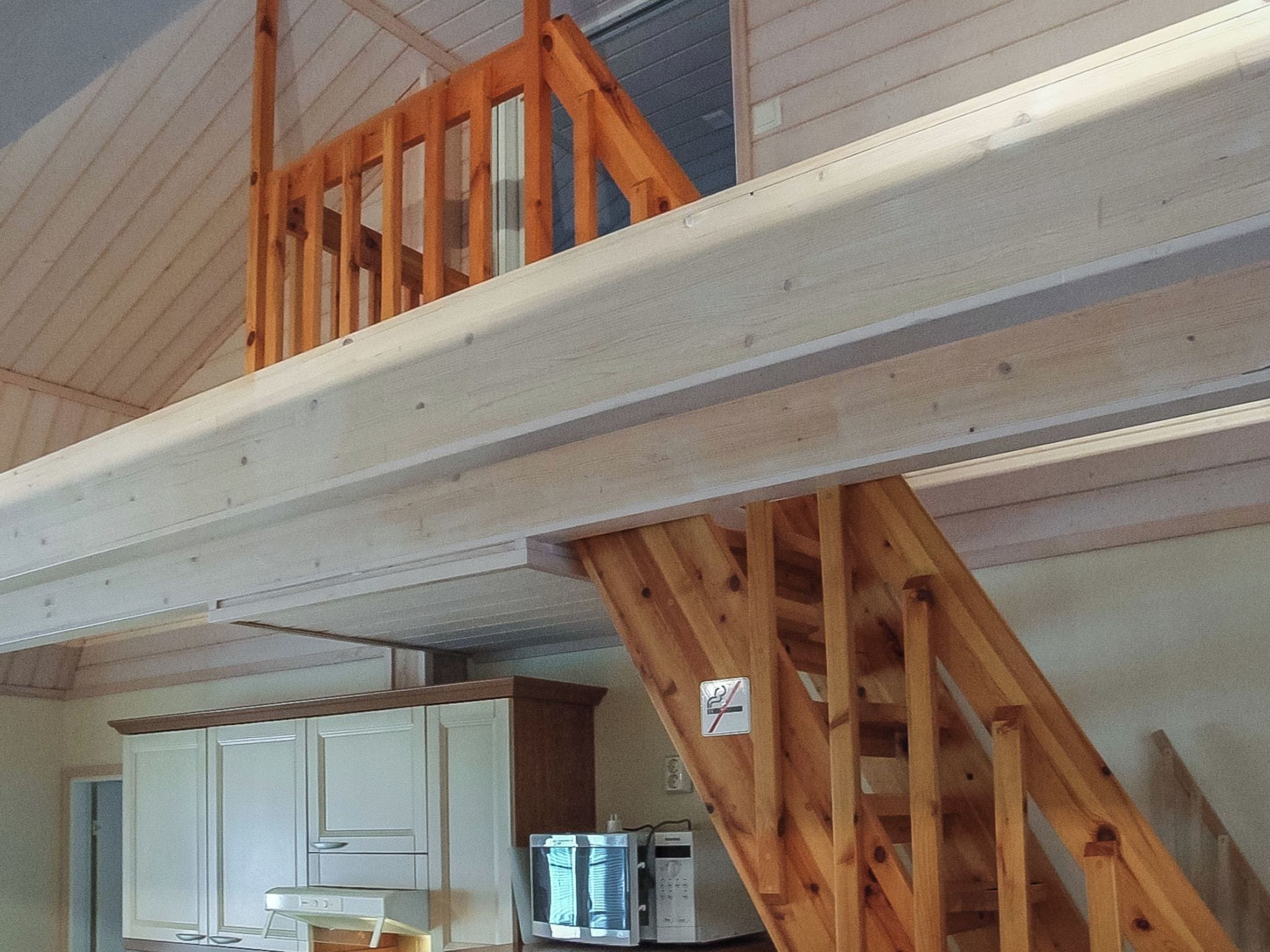 Un escalier en bois mène à une mezzanine d’où l’on a vue sur la cuisine et les placards.