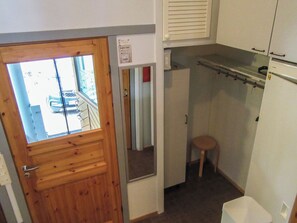 A compact kitchen with a wooden door, a small stool, and a white trash bin. - Kelokivakka d19 by Interhome (Kuusamo)