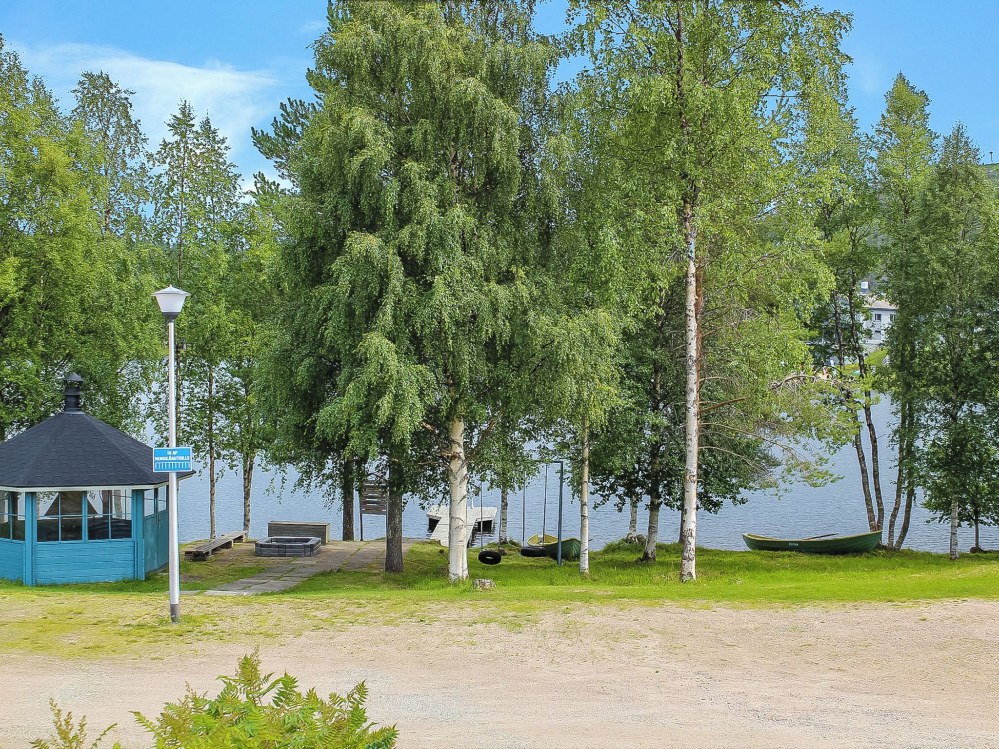 Un kiosque avec un toit bleu et une enseigne, entouré d’arbres et bordé par un plan d’eau.