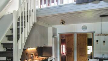 A modern kitchen with a built-in oven, a sink, and a staircase leading to a loft area.