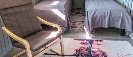 Una habitación con dos camas individuales, una silla de madera y un tapete estampado.