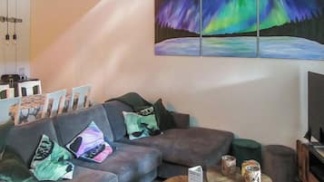 Een moderne woonkamer met een bank, kussens, een salontafel en een schilderij van het Noorderlicht.