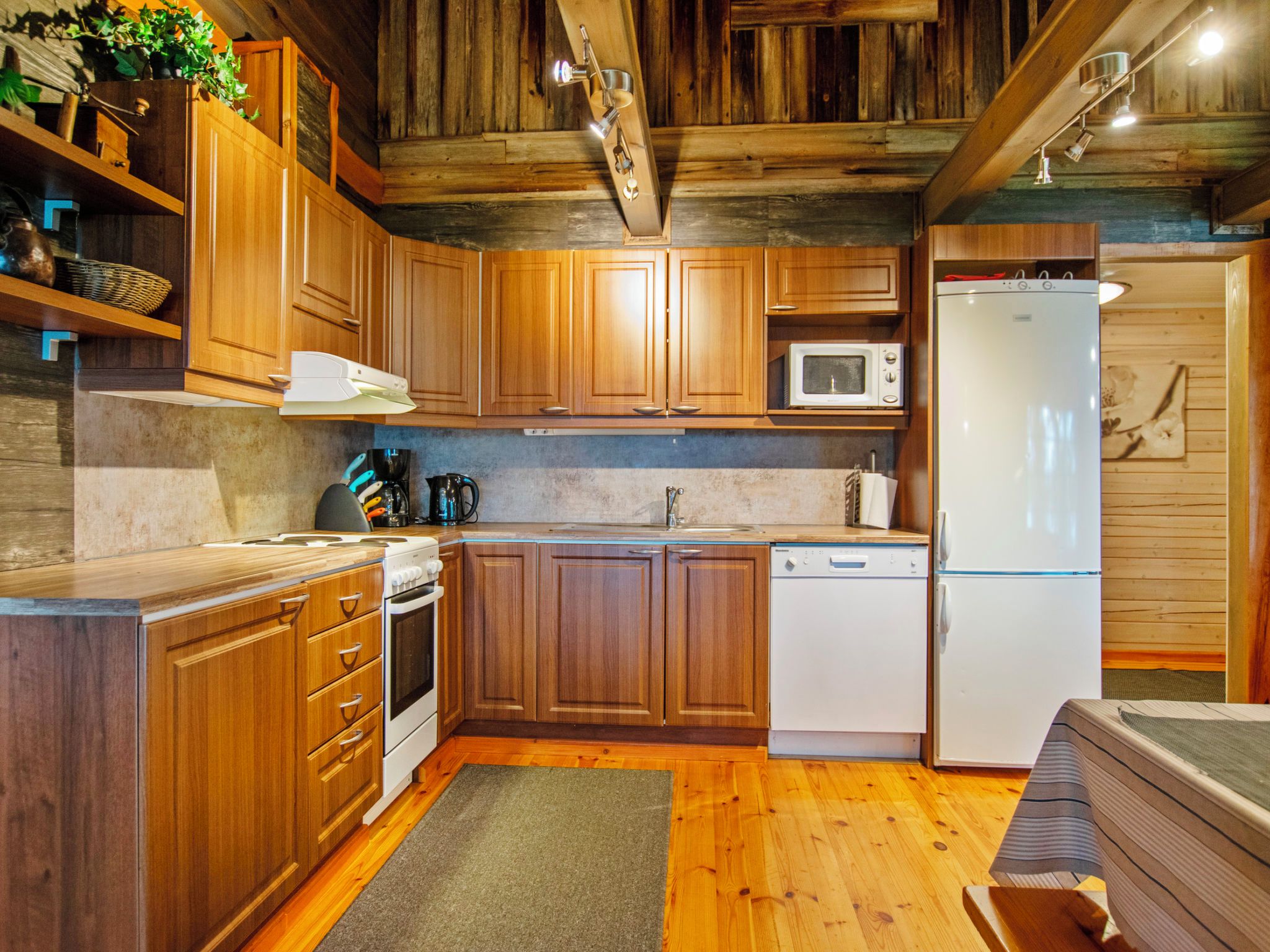 A kitchen with wooden cabinets, a microwave, a refrigerator, and a stove.