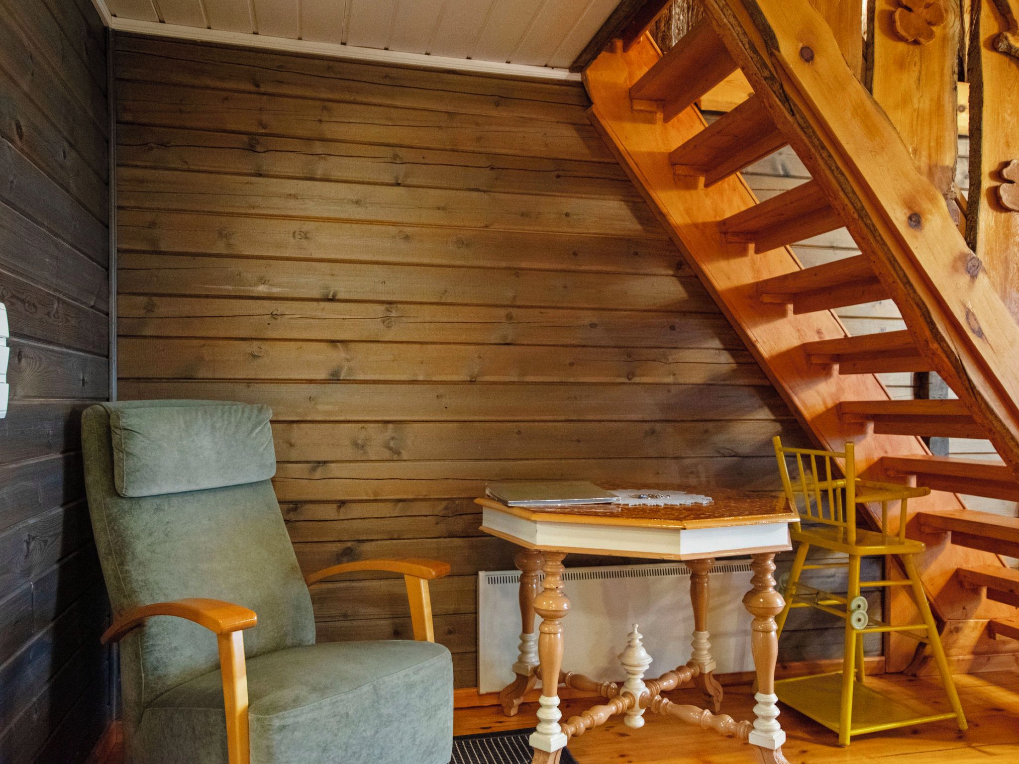 Un interior de madera con una silla, una mesa y una escalera de madera.