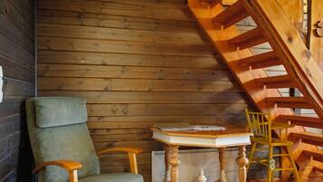 Un interior de madera con una silla, una mesa y una escalera de madera.