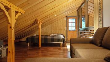 A cozy attic bedroom with a bed, a wooden ceiling, and a window.
