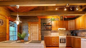 A cozy cabin-style kitchen with wooden cabinets, a stove, and a sink.
