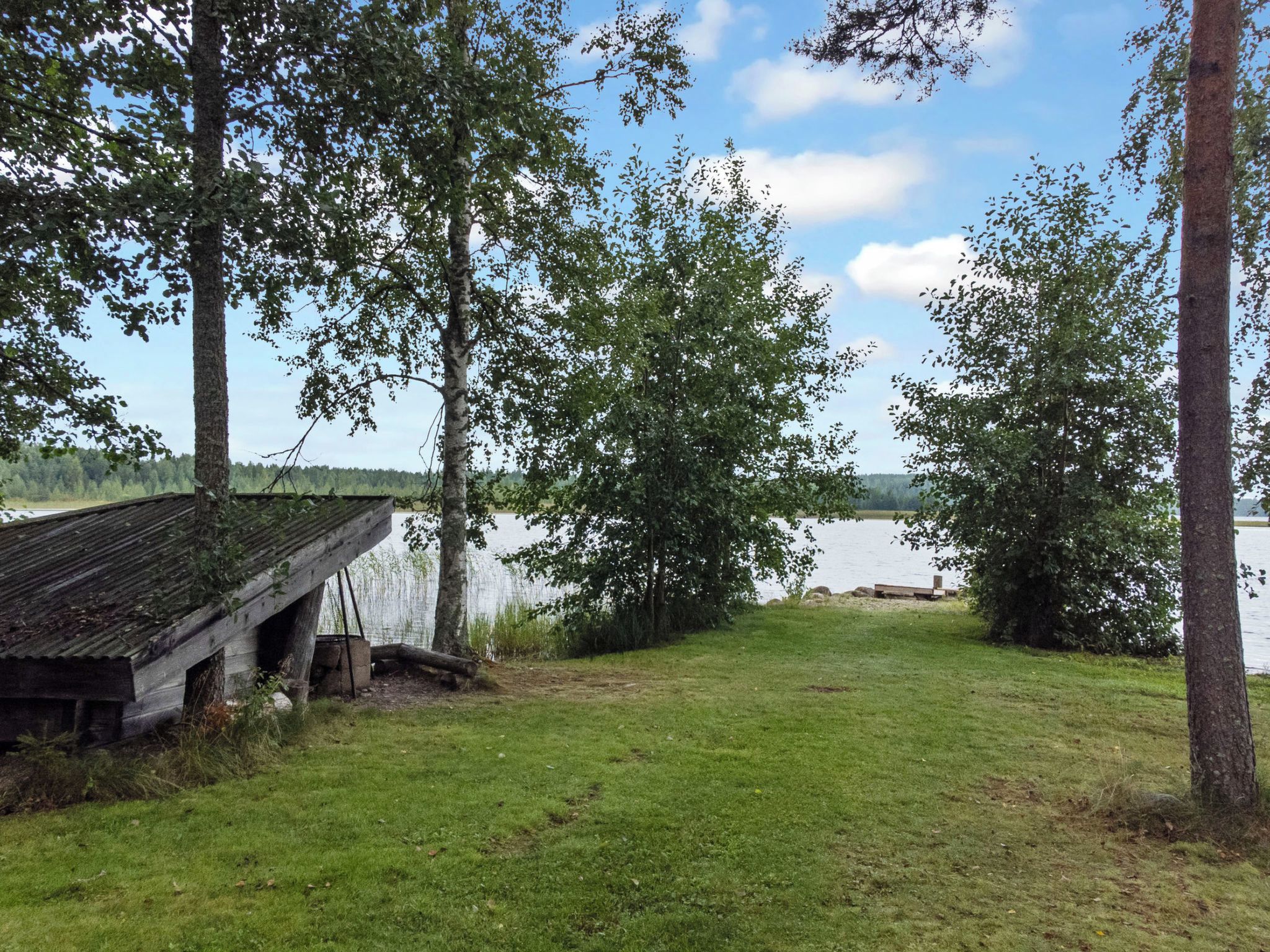 A lakeside cabin with a wooden deck and a view of the water.