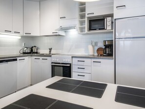 Une cuisine moderne avec des meubles blancs, un four à micro-ondes, une machine à café et un lave-vaisselle Siemens.