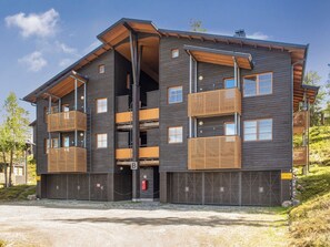 A multi-story building with balconies, a garage, and a gravel driveway.