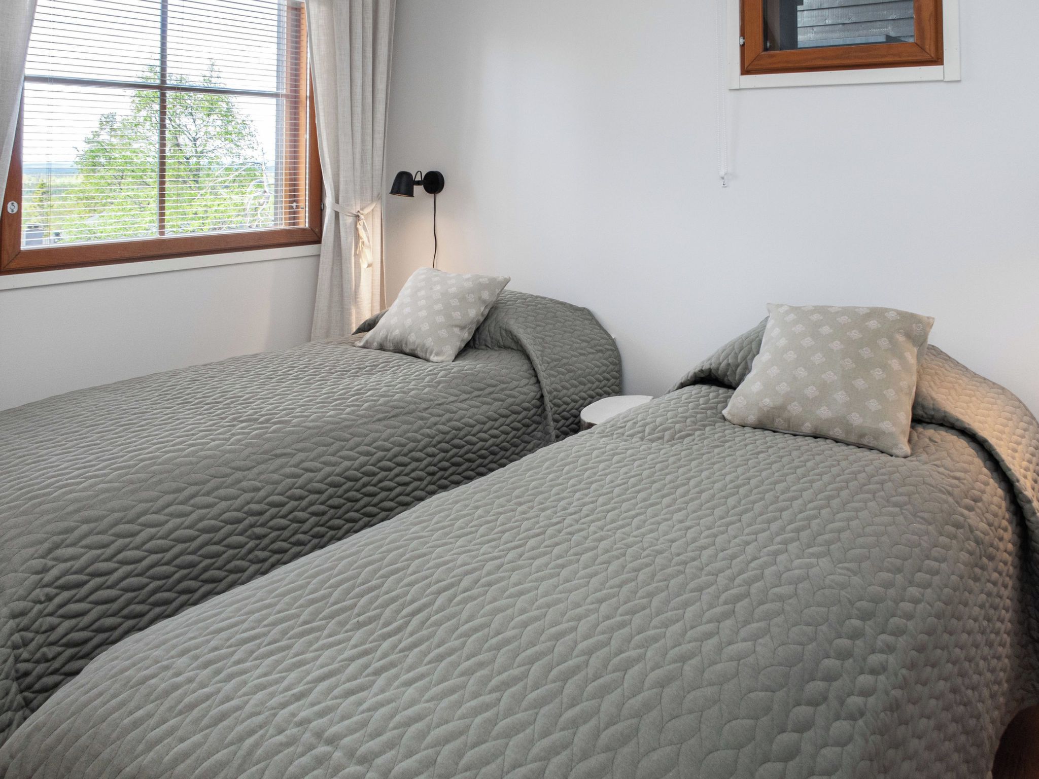 Une chambre à coucher avec deux lits, chacun étant agrémenté d’une couvre-lit matelassé et de coussins.