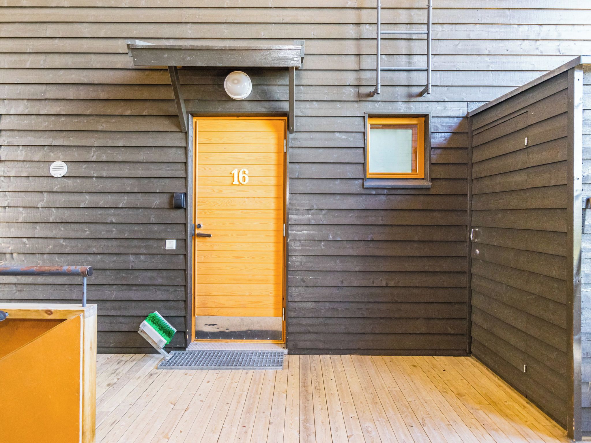 A wooden door with the number 16, a small window, and a metal ladder on the wall.