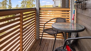 Une terrasse en bois avec une table en verre et deux chaises en osier.