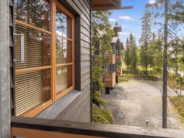 A wooden building with large windows and a view of a forested area.