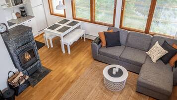 Un salon moderne avec une cheminée, un canapé, une table basse et un coin repas comprenant une table et des chaises.