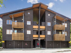 Un immeuble à plusieurs étages doté de balcons, d’une entrée principale et d’un garage.