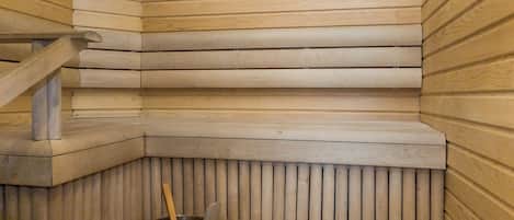 A sauna with a wooden bench and a metal bucket.