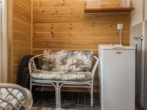 A compact bathroom with wooden walls, a white sink, and a small white refrigerator.