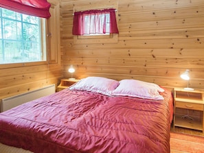 Een kamer met houten vloeren, een bed, twee bedlampen en een raam met gordijnen.