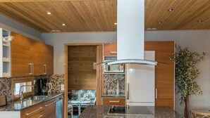 Une cuisine moderne avec des meubles en bois, un îlot central et un réfrigérateur encastré.