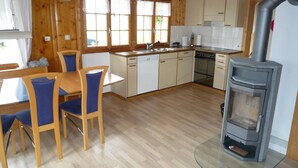 A wooden interior with a dining area, kitchen, and a wood stove. - Ferienhaus Niesen View by Interhome (Erlenbach)