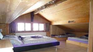 A wooden attic bedroom with bunk beds and a desk. - Ferienhaus Niesen View by Interhome (Erlenbach)