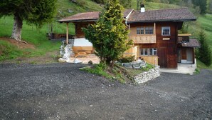 A two-story wooden house with a stone foundation, a wooden deck, and a chimney. - Ferienhaus Niesen View by Interhome (Erlenbach)