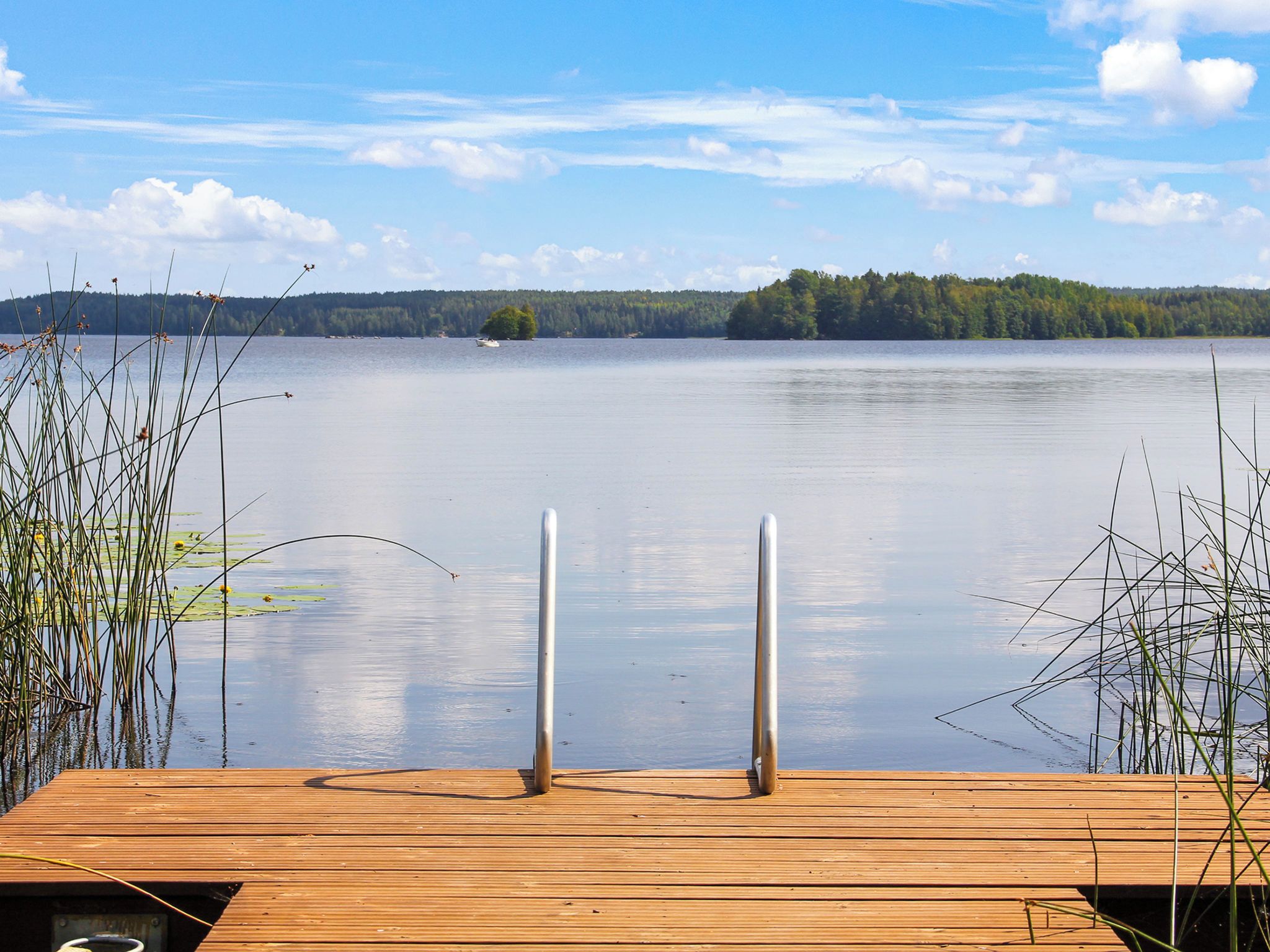 Une jetée en bois s’étendant sur un lac paisible, sous un ciel dégagé.