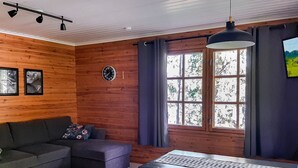 Um quarto aconchegante com parede de madeira, um sofá, uma mesa e uma janela com cortinas.