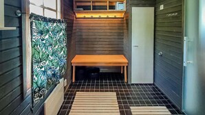 Casa de banho pequena e fechada com um banco, uma prateleira com livros e uma porta com puxador.