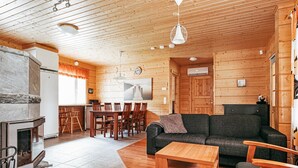 A cozy cabin interior with a dining area, a living room with a sofa and coffee table, and a fireplace. - Aapeli iso by Interhome (Ähtäri)