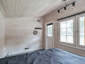 A bedroom with a bed, a window, a door, and a wall-mounted light fixture. - Aapeli iso by Interhome (Ähtäri)