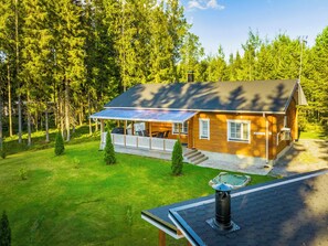 A wooden cabin with a covered porch, surrounded by a forest. - Aapeli iso by Interhome (Ähtäri)