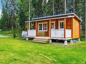 A wooden cabin with a porch, surrounded by a grassy area and trees. - Aapeli iso by Interhome (Ähtäri)