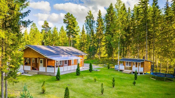 A cabin with a covered porch and a separate building with a trampoline. - Aapeli iso by Interhome (Ähtäri)