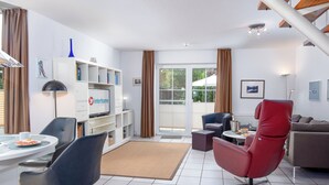 Un salon moderne avec un téléviseur, des sièges et une bibliothèque.