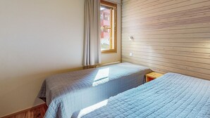 Un dormitorio con dos camas, una ventana con cortinas y paneles de madera en una pared.