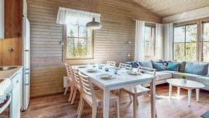 Un interior de cabaña moderno con comedor, sofá y cocina.