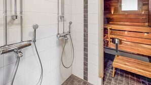 Un baño con ducha, un banco de madera y suelo de baldosas.
