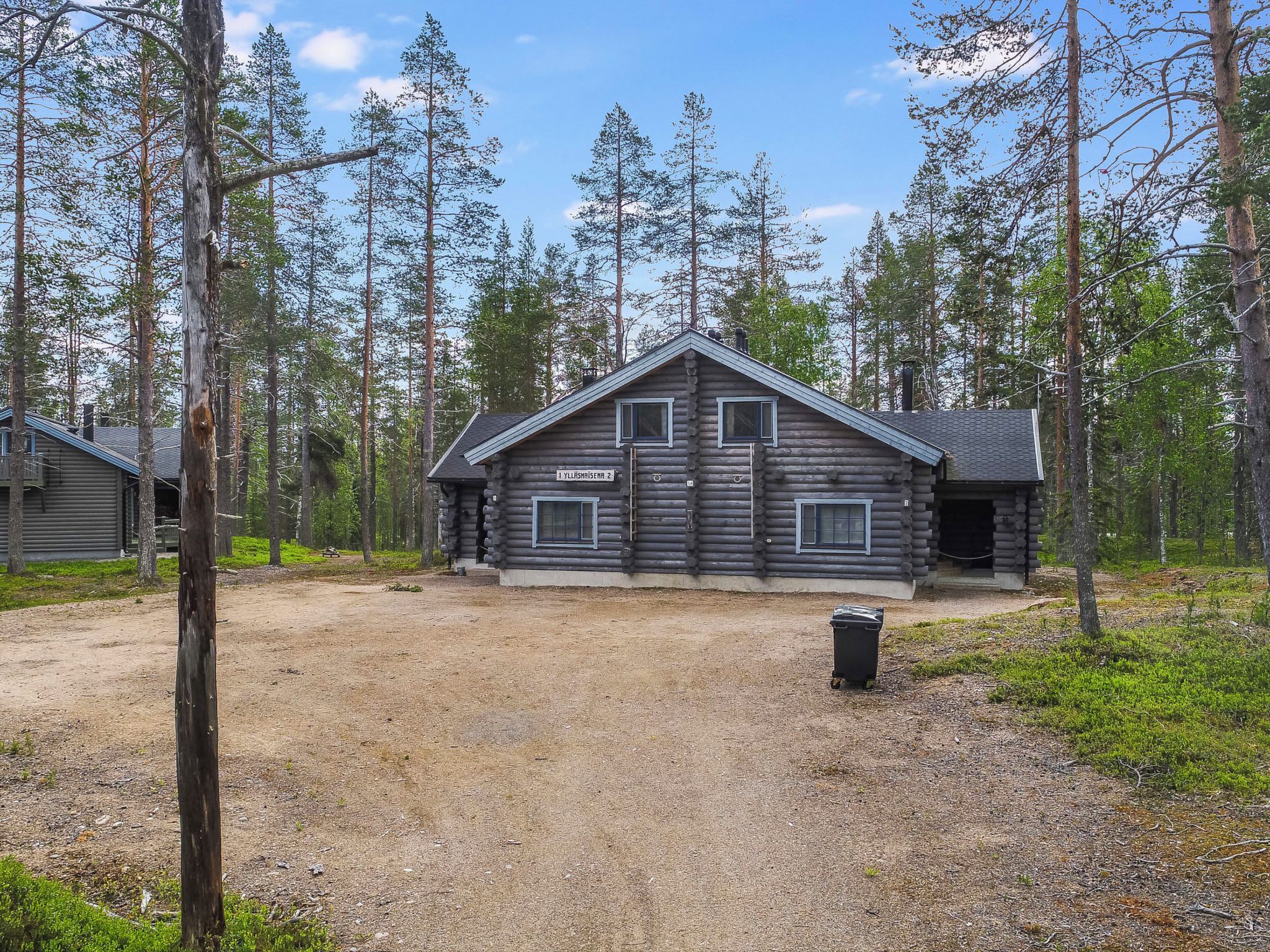 A log cabin with a clear sky, surrounded by tall trees.