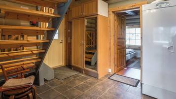 A compact kitchen with a built-in refrigerator, wooden cabinets, and a staircase leading to a loft area.