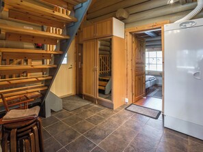 A compact kitchen with a built-in refrigerator, wooden cabinets, and a staircase leading to a loft area.