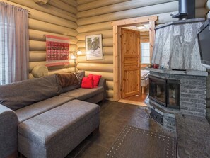 A log cabin interior with a sofa, fireplace, and wooden walls.