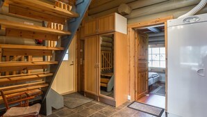Eine kleine Küche mit eingebautem Herd, Holzregalen und einer Treppe, die zu einem Schlafbereich im oberen Geschoss führt.