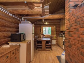 A cabin interior with a wooden dining table, a refrigerator, and a microwave. - Harrila by Interhome (Mikkeli)