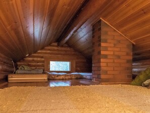 An attic bedroom with a sloped ceiling, a small window, and a brick chimney. - Harrila by Interhome (Mikkeli)