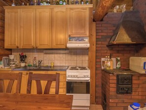 A kitchen with wooden cabinets, a stove, and a brick oven. - Harrila by Interhome (Mikkeli)