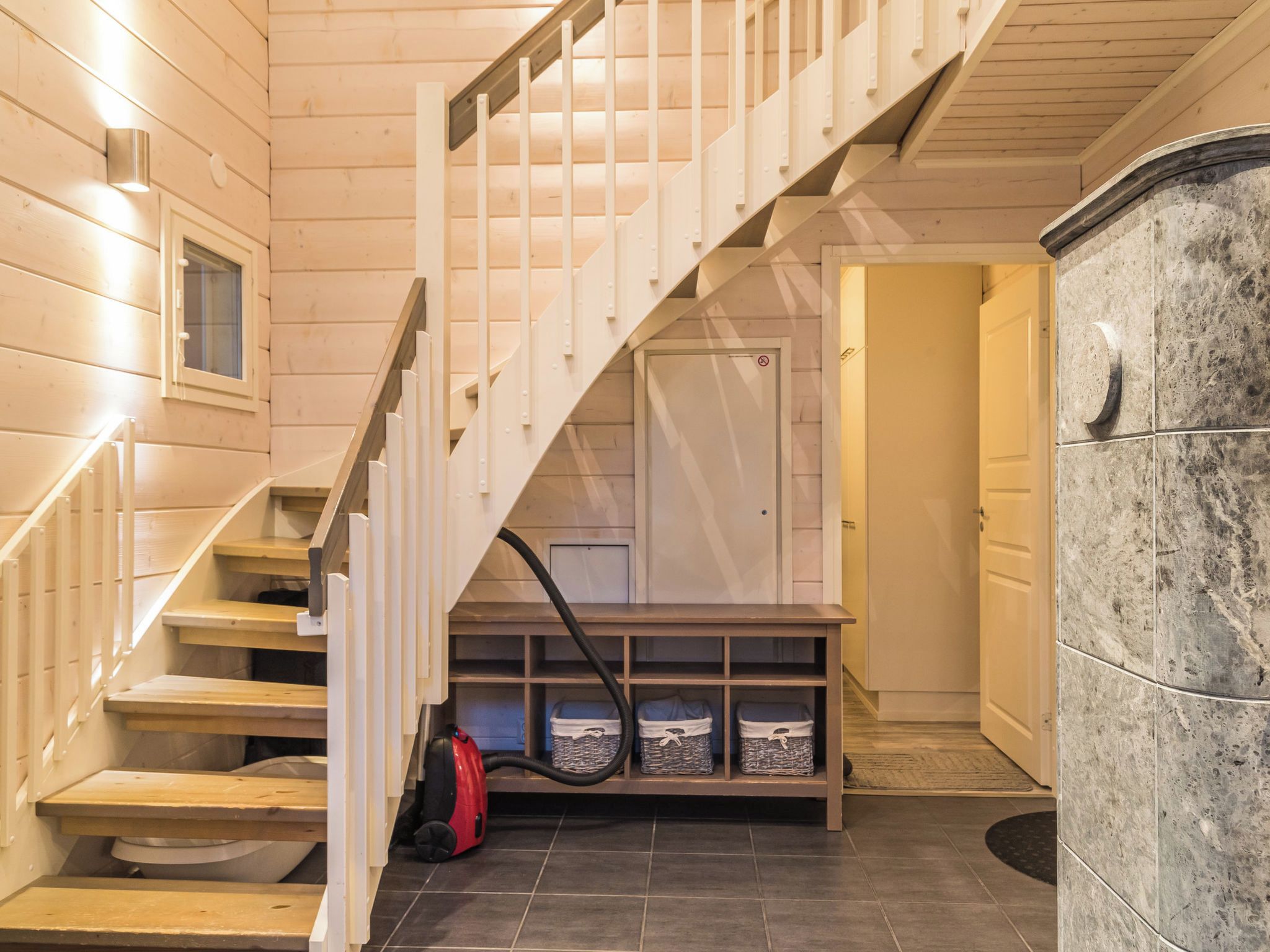 A wooden staircase leading to a landing with a bench and storage bins.