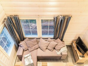 A cozy room with a sofa, two windows with curtains, a television, and a small table. - Levin ahmahovi 1a by Interhome (Kittilä)