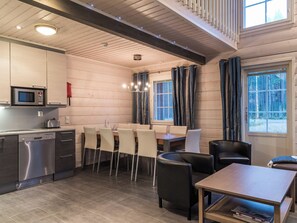 A modern kitchen with a microwave, toaster, and dishwasher. There is a dining area with chairs and a table, and a seating area with a sofa and a coffee table. - Levin ahmahovi 1a by Interhome (Kittilä)